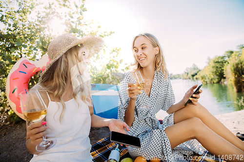 Image of Young lesbian\'s couple having fun and spending time at riverside in sunny day