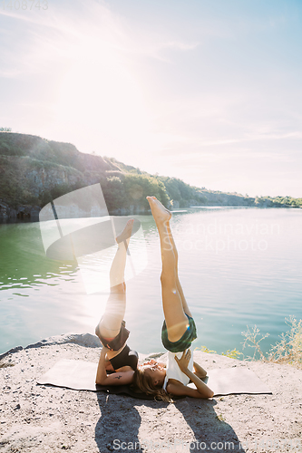 Image of Young lesbian\'s couple exercizing yoga at riverside in sunny day