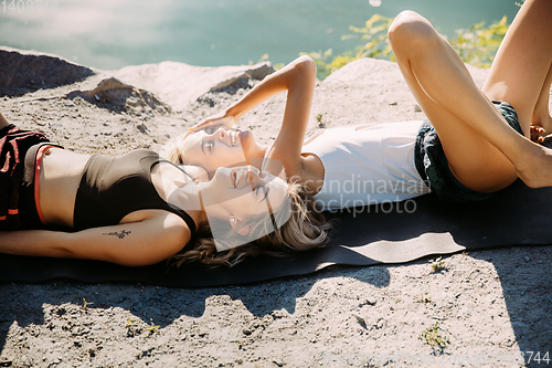 Image of Young lesbian\'s couple exercizing yoga at riverside in sunny day