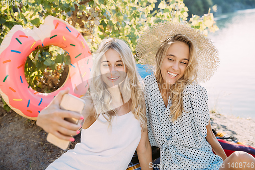 Image of Young lesbian\'s couple having fun and spending time at riverside in sunny day