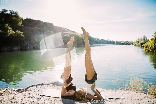 Image of Young lesbian\'s couple exercizing yoga at riverside in sunny day