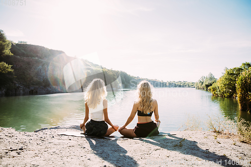 Image of Young lesbian\'s couple exercizing yoga at riverside in sunny day