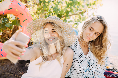 Image of Young lesbian\'s couple having fun and spending time at riverside in sunny day