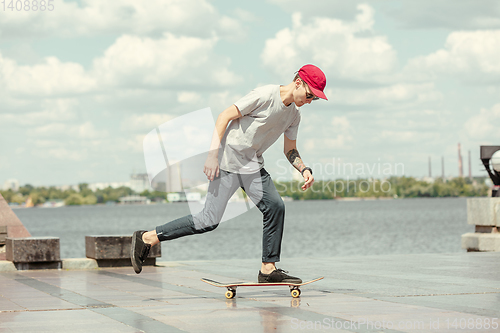 Image of Skateboarder doing a trick at the city\'s street in sunny day