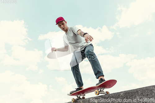 Image of Skateboarder doing a trick at the city\'s street in sunny day