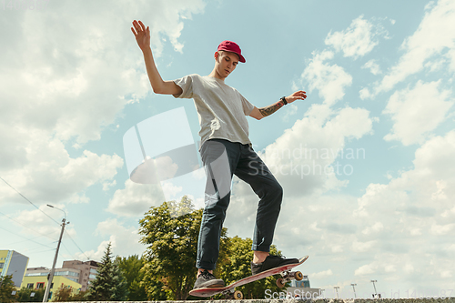 Image of Skateboarder doing a trick at the city\'s street in sunny day