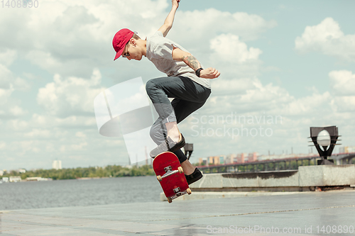 Image of Skateboarder doing a trick at the city\'s street in sunny day