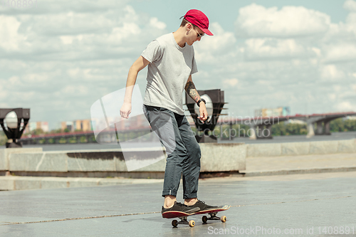 Image of Skateboarder doing a trick at the city\'s street in sunny day