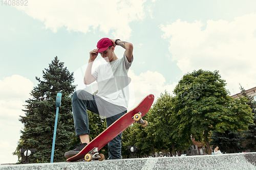 Image of Skateboarder doing a trick at the city\'s street in sunny day