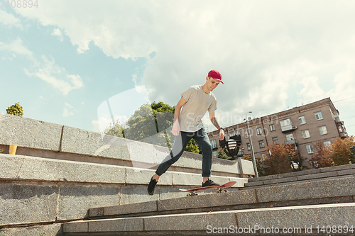 Image of Skateboarder doing a trick at the city\'s street in sunny day