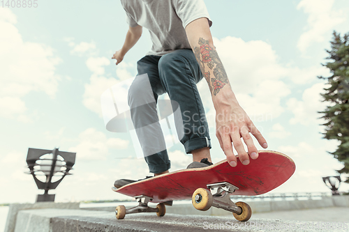 Image of Skateboarder doing a trick at the city\'s street in sunny day