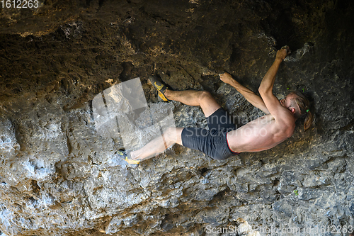 Image of Young male climber bouldering a rock wall in a cave