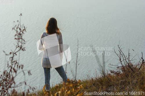 Image of Girl stands on a hill and looks at the sea, rear view
