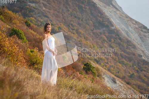 Image of A beautiful girl stands on a hill by the sea