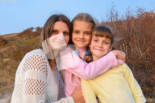 Image of Portrait of a happy girl with two daughters on the background of nature