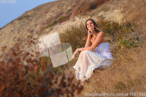 Image of A girl in a white dress enjoys a beautiful view of the sunset