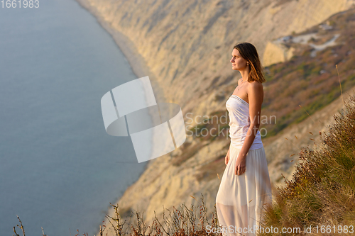 Image of Beautiful slender girl in a white dress on the background of a beautiful mountain and sea landscape