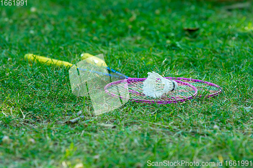 Image of On the green grass are badminton rackets and a shuttlecock