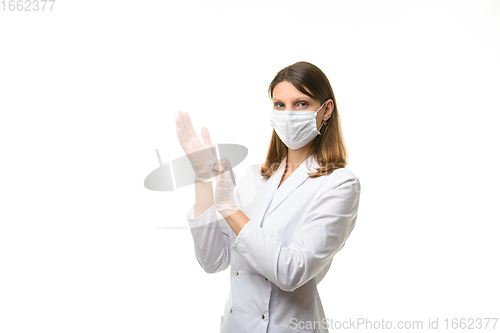 Image of Girl doctor puts on transparent medical gloves on her hands, and looks into the frame