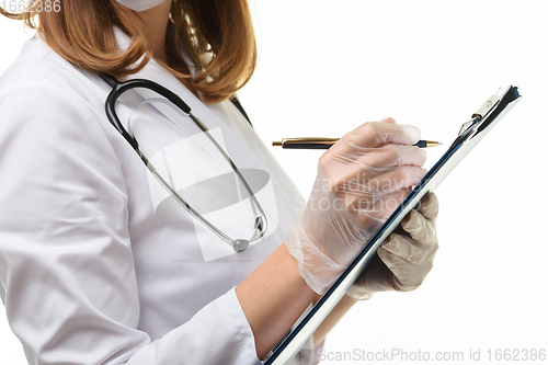 Image of Hands of a doctor in gloves writes with a ballpoint pen in a tablet, close-up