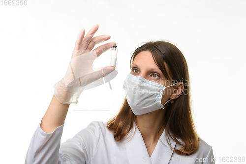 Image of Doctor looks closely at the drug in a test tube, focusing on the test tube