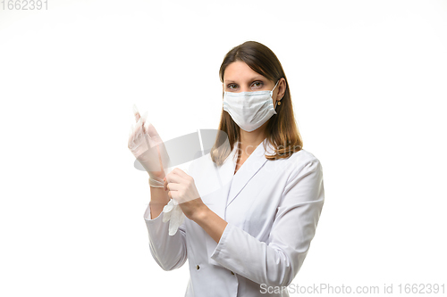 Image of Girl doctor puts on transparent medical gloves on her hands and looks into the frame