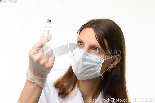 Image of Girl doctor look at glass test tube with white powder, focus on test tube