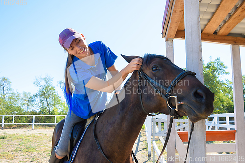 Image of Girl after equestrian training joyfully looks at the horse\'s face