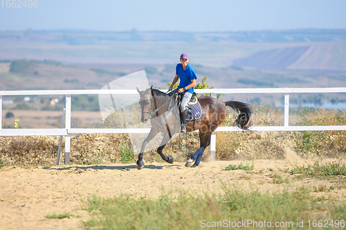 Image of A girl on a horse ride rides a horse in the corral