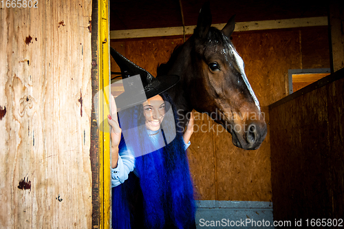 Image of A girl dressed as a witch holds a horse in a paddock