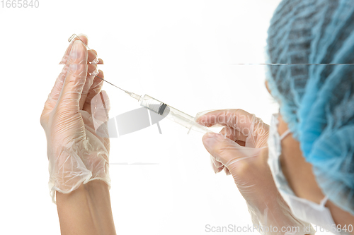 Image of A medical professional draws a medicine from an ampoule with a syringe