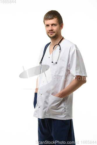 Image of Portrait of a male doctor, hands stuck in pockets, a phonendoscope hangs around his neck, isolated on white background