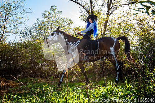 Image of Girl dressed as a witch riding a horse in halloween celebration