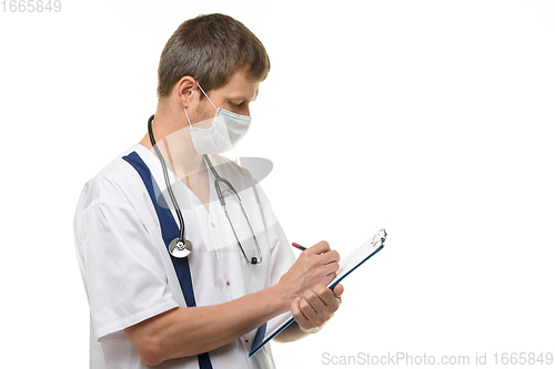Image of Male doctor writes with his right hand in a clipboard with a ballpoint pen