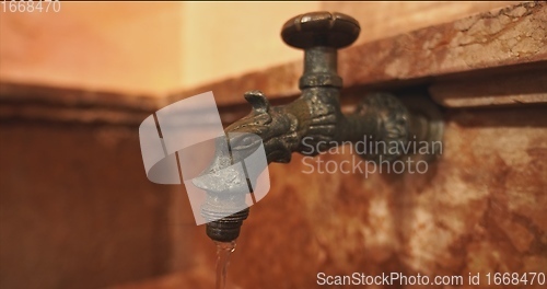 Image of Old stone wash basin with decorative tap with water flowing