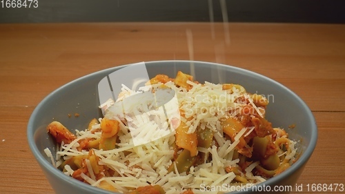Image of Cheese topping beiing applied to bowl of pasta in camera motion