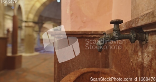 Image of Old stone wash basin with decorative tap with water flowing