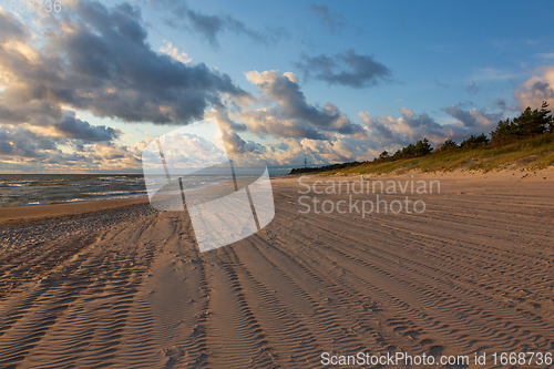 Image of Wild sandy beach under cloudy sky of sunset