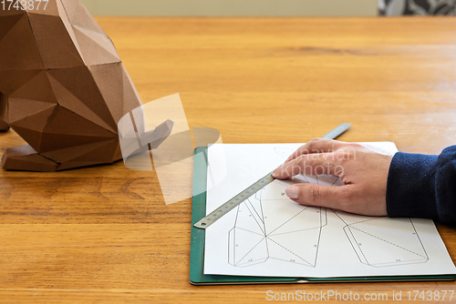 Image of Somebody is making a cube sculpture with paper and linear