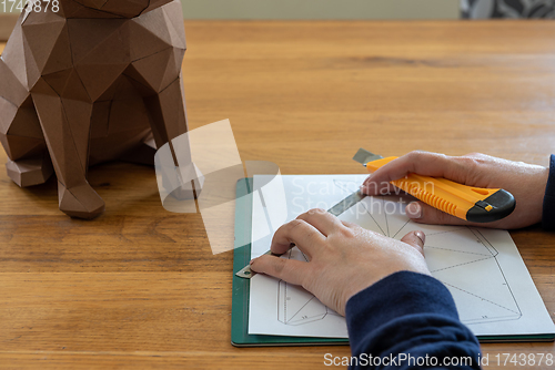 Image of Somebody is making a cube sculpture with paper, linear and knife