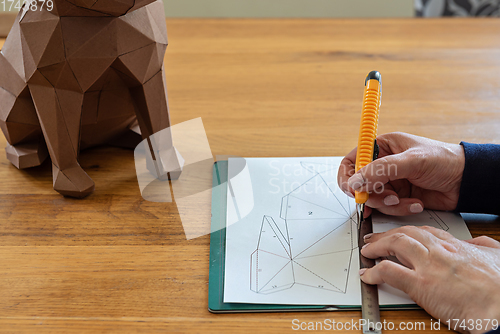 Image of Somebody is making a cube sculpture with paper, linear and knife