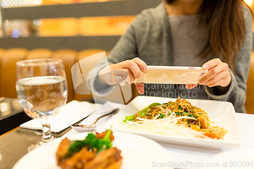 Image of Woman taking photo on dishes in restaurant