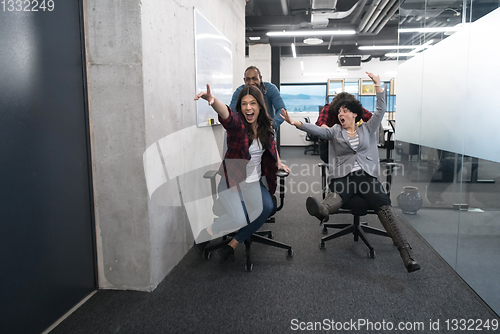 Image of multiethnics business team racing on office chairs