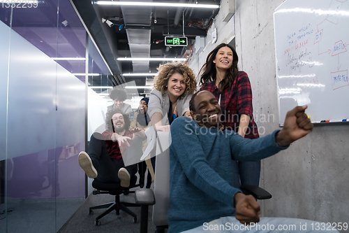 Image of multiethnics business team racing on office chairs