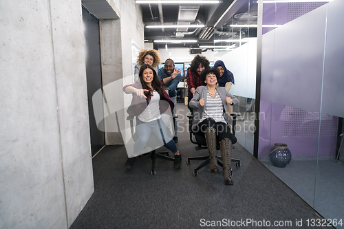 Image of multiethnics business team racing on office chairs