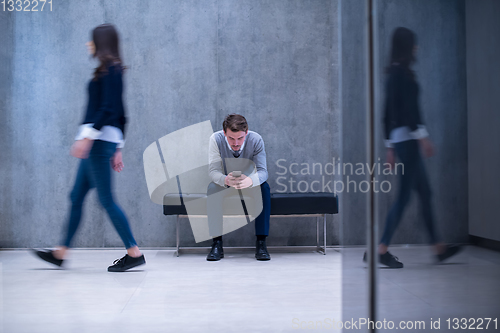 Image of businessman using mobile phone while sitting on the bench