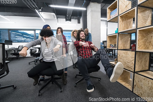 Image of multiethnics business team racing on office chairs