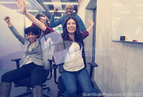 Image of multiethnics business team racing on office chairs