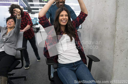 Image of multiethnics business team racing on office chairs