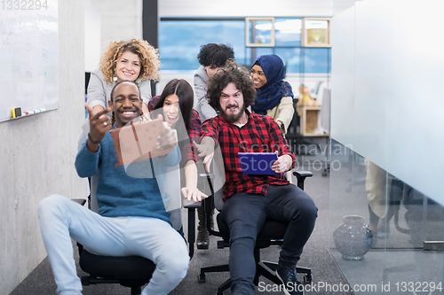 Image of multiethnics business team racing on office chairs